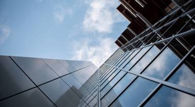 Hoog shot van een modern gebouw (provinciehuis Overijssel) met glazen gevel tegen een blauwe lucht.
